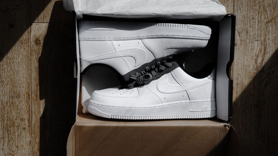 Crisp white Nike sneakers displayed in an open box on a wooden surface, showcasing product elegance.
