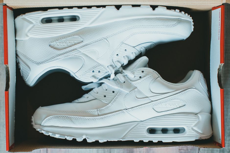 White sneakers in a shoebox viewed from above, showcasing clean design.